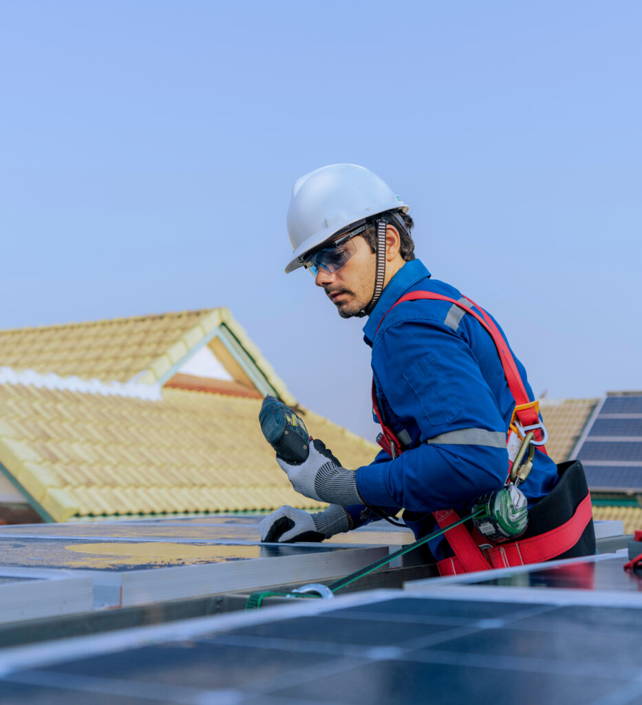 Male engineer in protective helmet installing solar photovoltaic panel system using screwdriver.