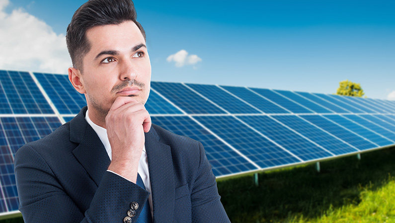 Portrait of thoughtful businessman standing outside near solar panels with copy space