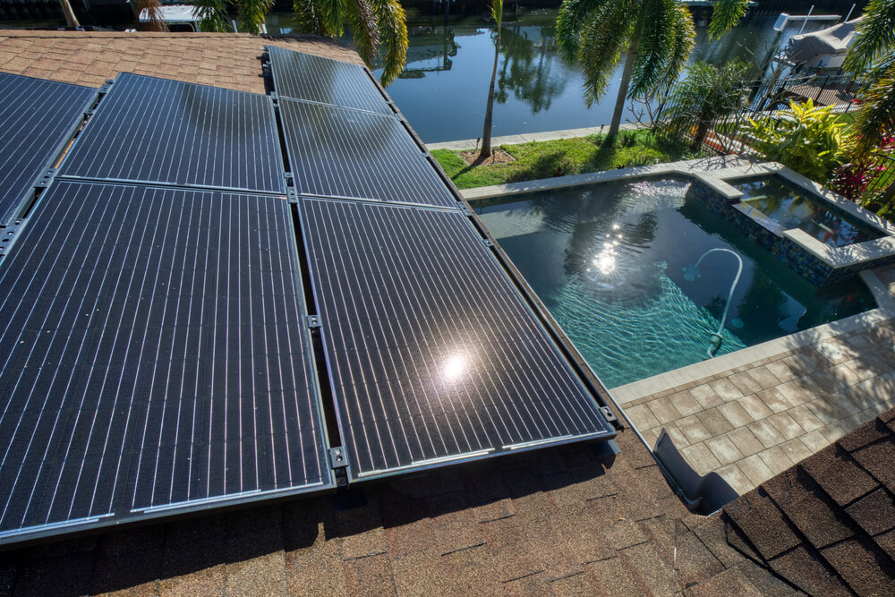 Solar panels on a roof in Florida with view of a pool and a canal.
