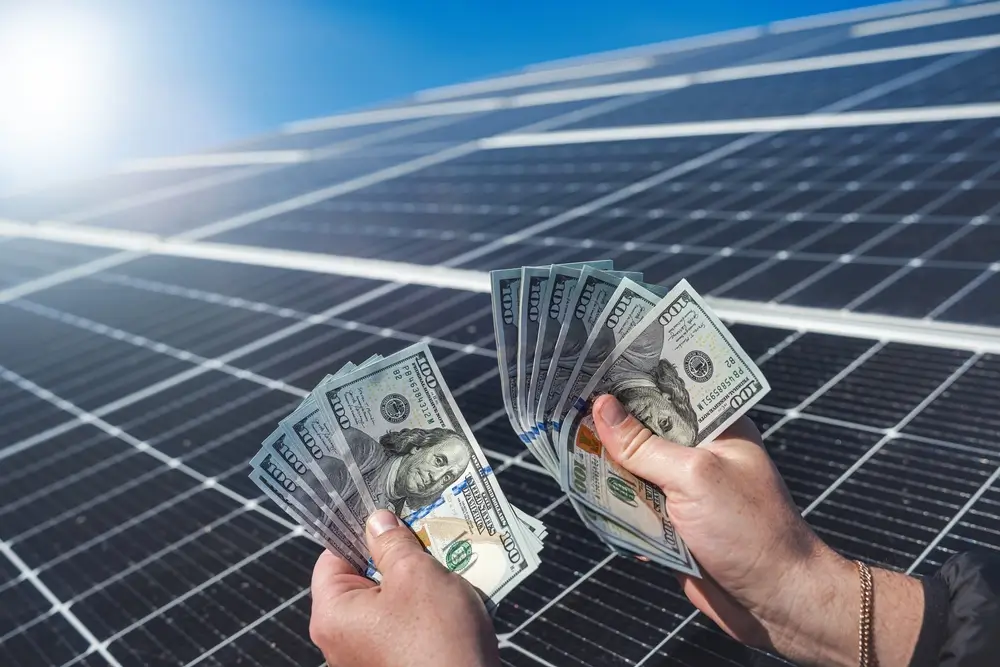 hand of a young man holding dollars to pay for the installation of new solar panels