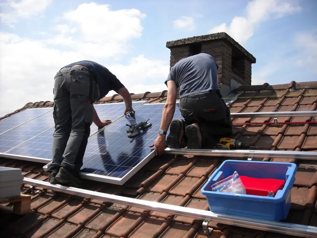two men on roof inspecting broken solar panels