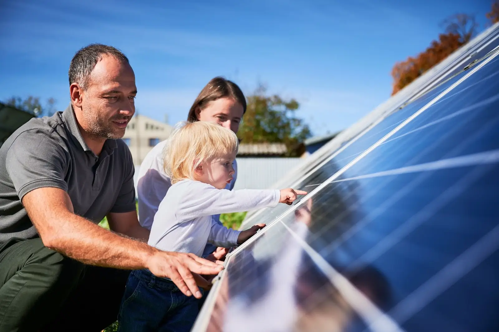 father, mother, and son looking at solar panels up close
